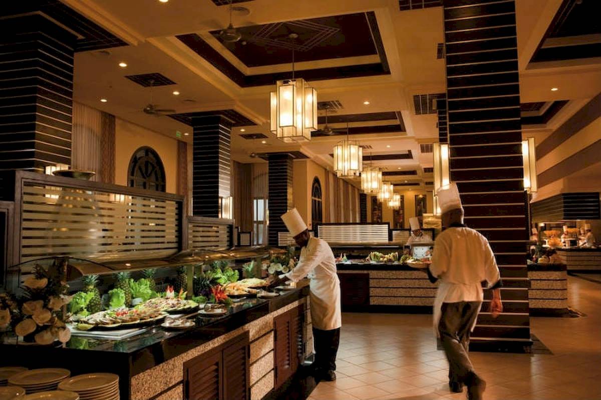 Im Riu Guanacaste Hotel bereitet ein Koch am Buffet Essen zu, während ein anderer Kellner vorbeigeht.