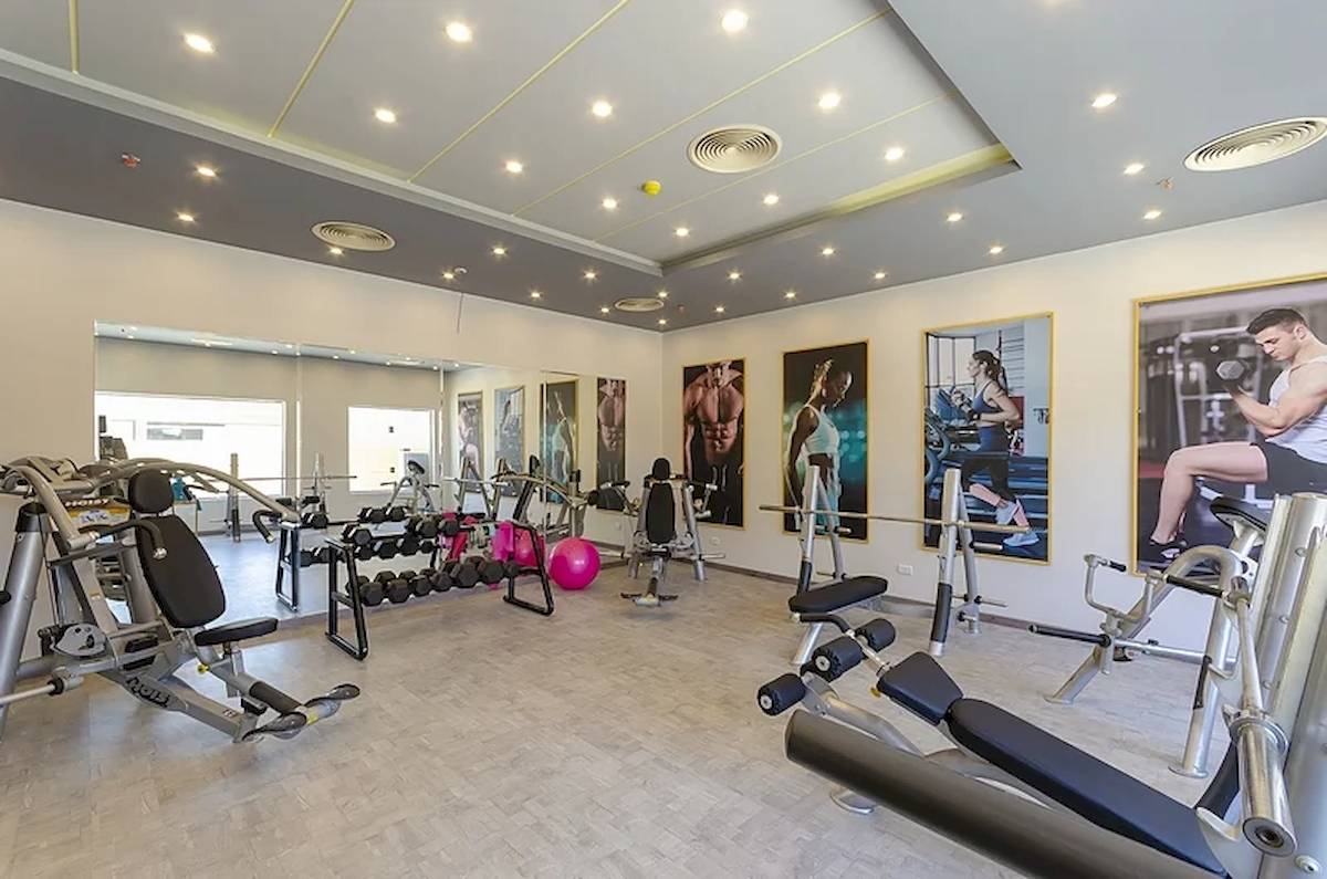 Innenansicht des Fitnesscenters im Titanic Royal Hotel mit verschiedenen Geräten und Plakaten.