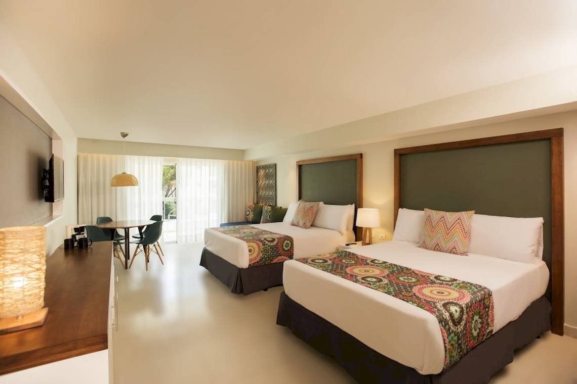 Doppelzimmer im Emotions By Hodelpa Hotel in Puerto Plata mit zwei Betten, Tisch und Stühlen.