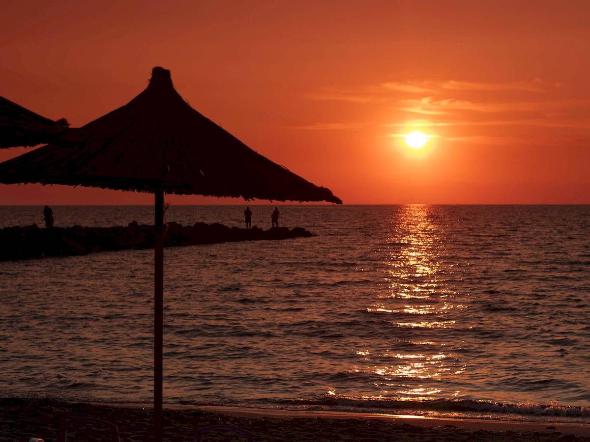 Sonnenuntergang am Strand mit Sonnenschirm und Liegen am Brilliant Hotel & Spa