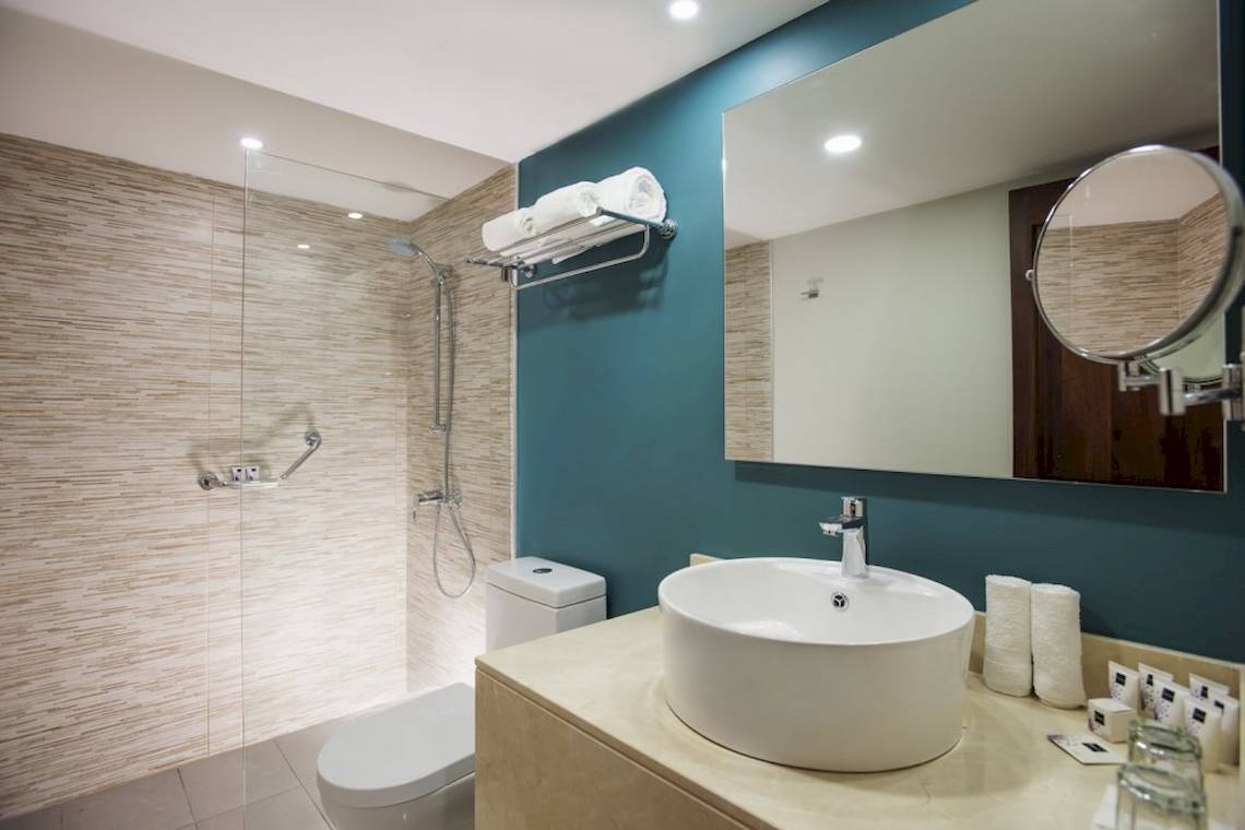 Badezimmer im Emotions By Hodelpa Puerto Plata Hotel mit Dusche, Toilette, Spiegel und Waschbecken.