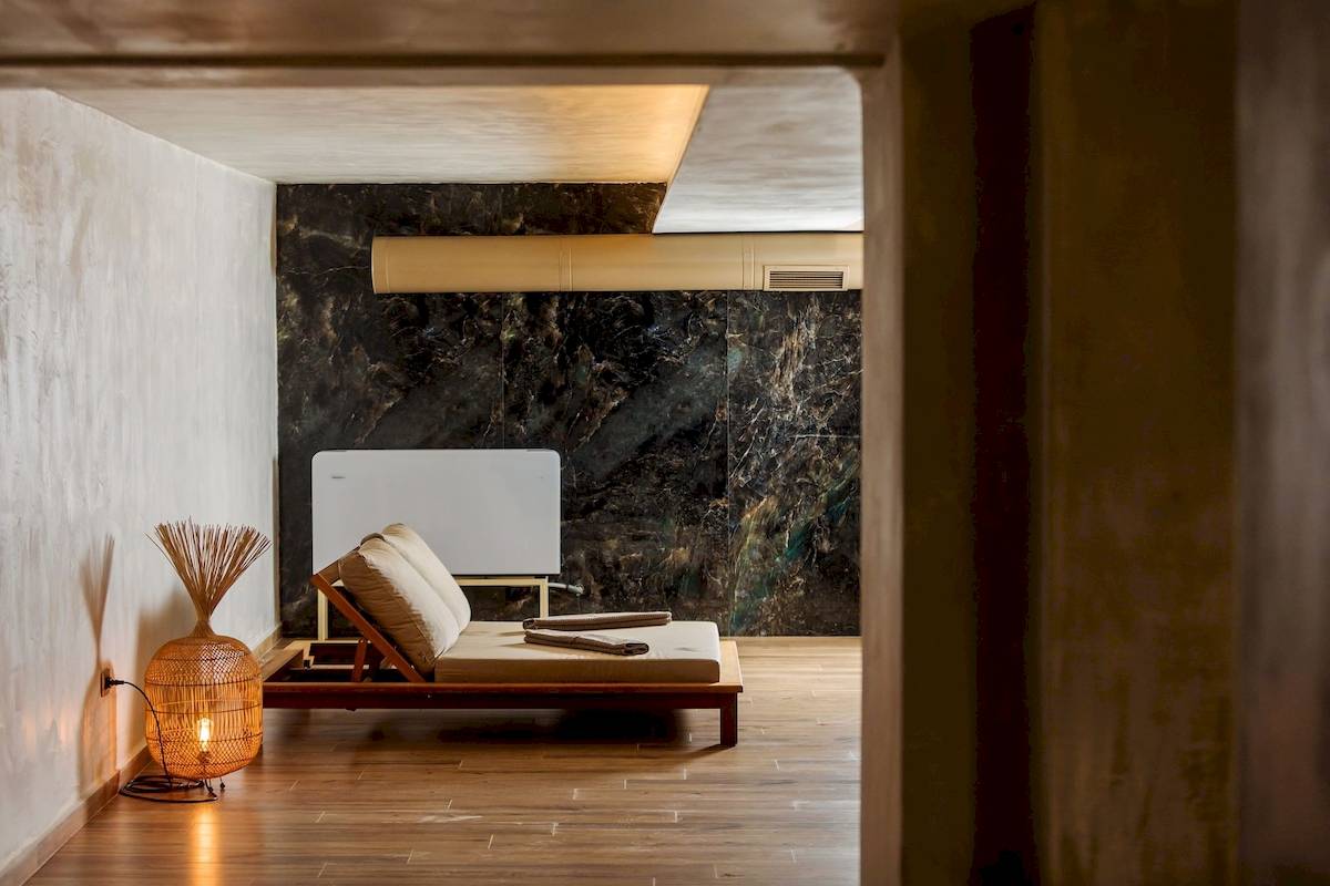 Loungebereich im Gloria Palace Hotel & SPA mit einem Chaiselongue, einer Lampe und einer Marmorwand.