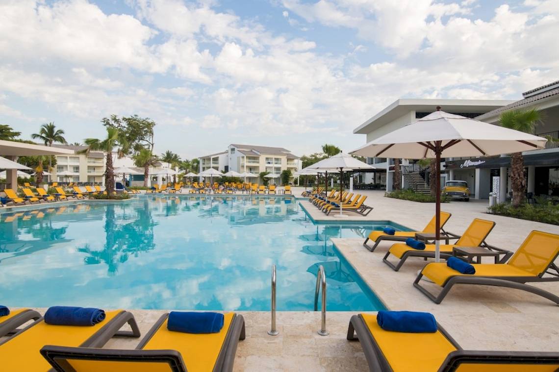 Außenpool des Emotions By Hodelpa Hotels mit gelben Liegestühlen und weißen Sonnenschirmen.