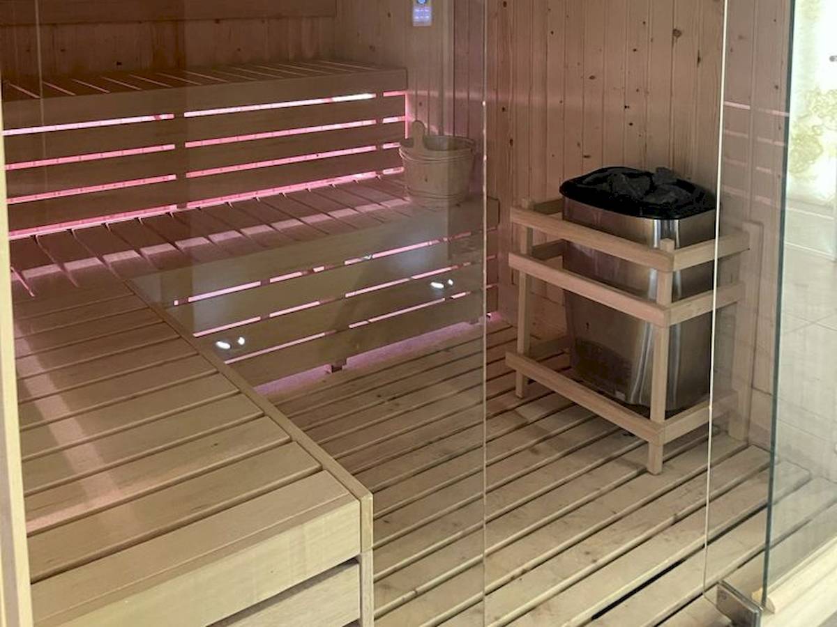 Innenansicht der Sauna im Klajdi Resort mit Holzwänden und Bänken, die mit roten Lichtern beleuchtet sind.