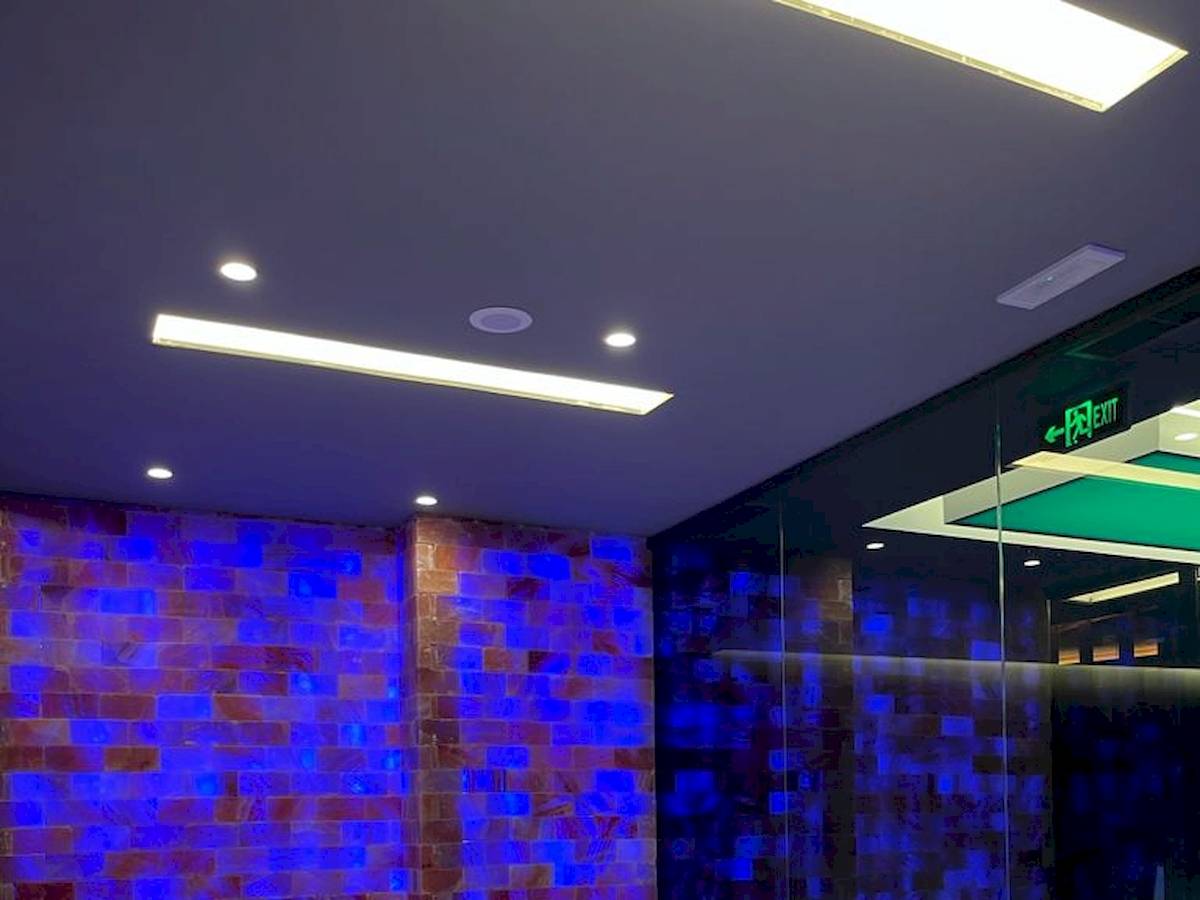 Innenbereich der Sauna im Klajdi Resort & SPA mit blauen und roten Lichtern und weißen Liegen.