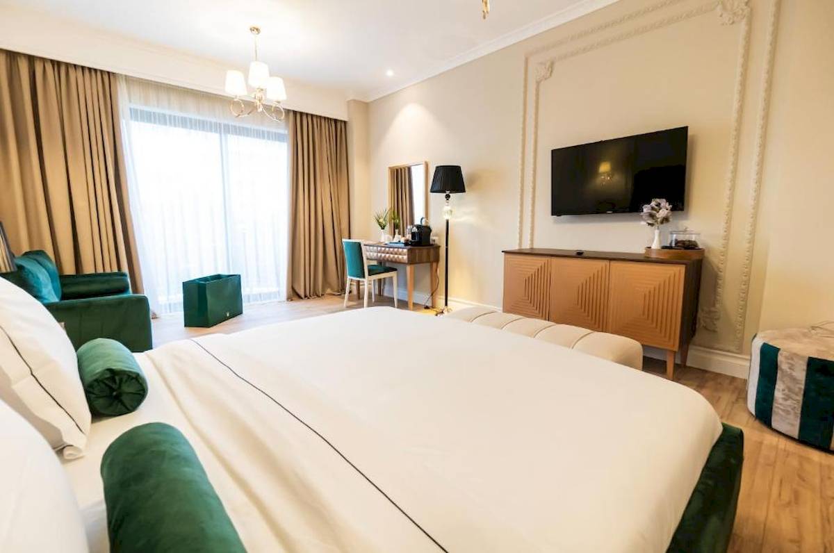 Schlafzimmer im Diamma Resort mit einem großen Bett, grünen Kissen und einem Fernseher an der Wand.