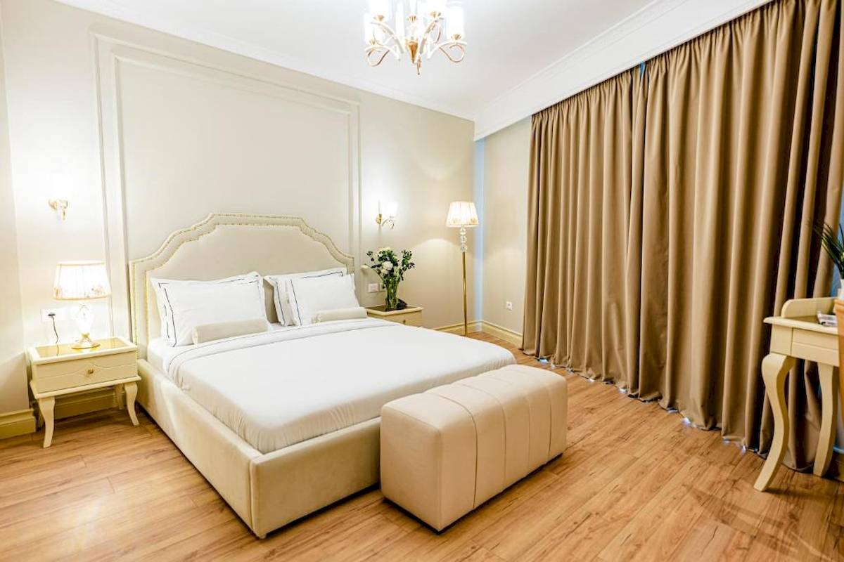 Schlafzimmer im Diamma Resort mit Doppelbett, Nachttischen, Lampen und beigem Vorhang.
