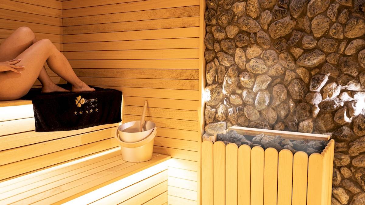 Eine Person genießt die Sauna im Diamma Resort mit einer Holzbank, einem Handtuch und einem Eimer.