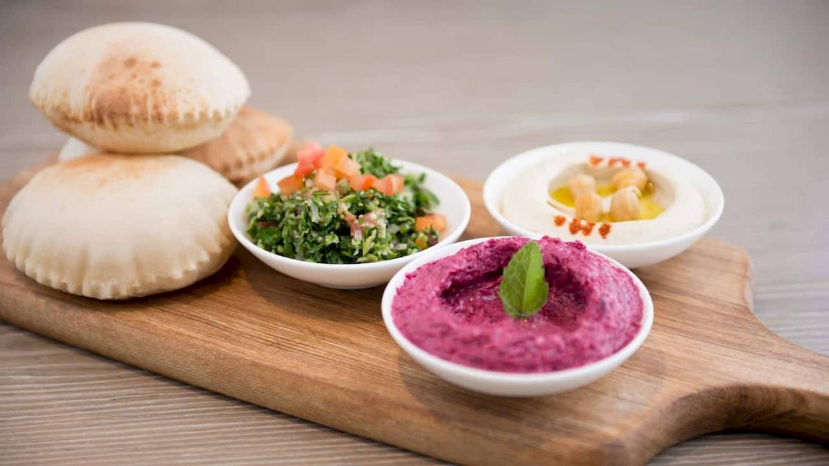 Ein Schneidebrett mit verschiedenen Hummus-Variationen und Pita-Brot