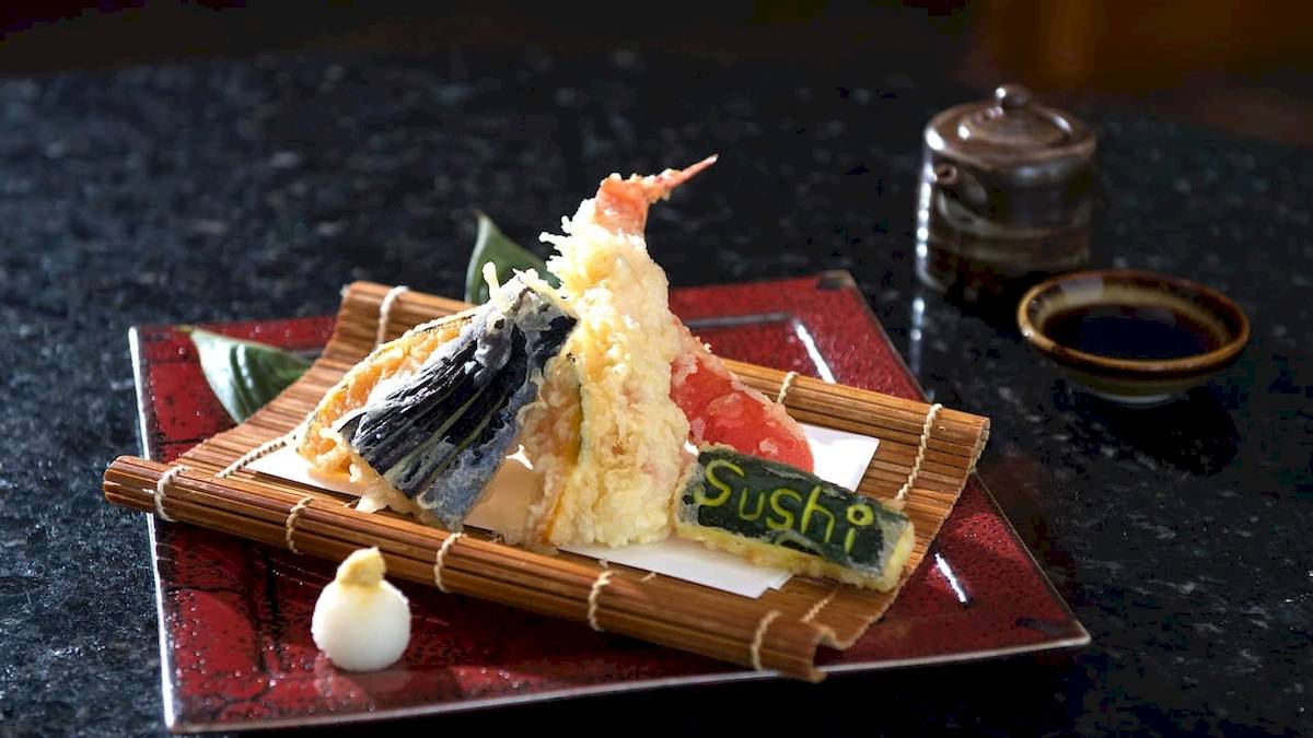 Ein Sushi-Teller mit verschiedenen Sushi-Stücken und einem Schriftzug, der Sushi auf dem Teller sagt.
