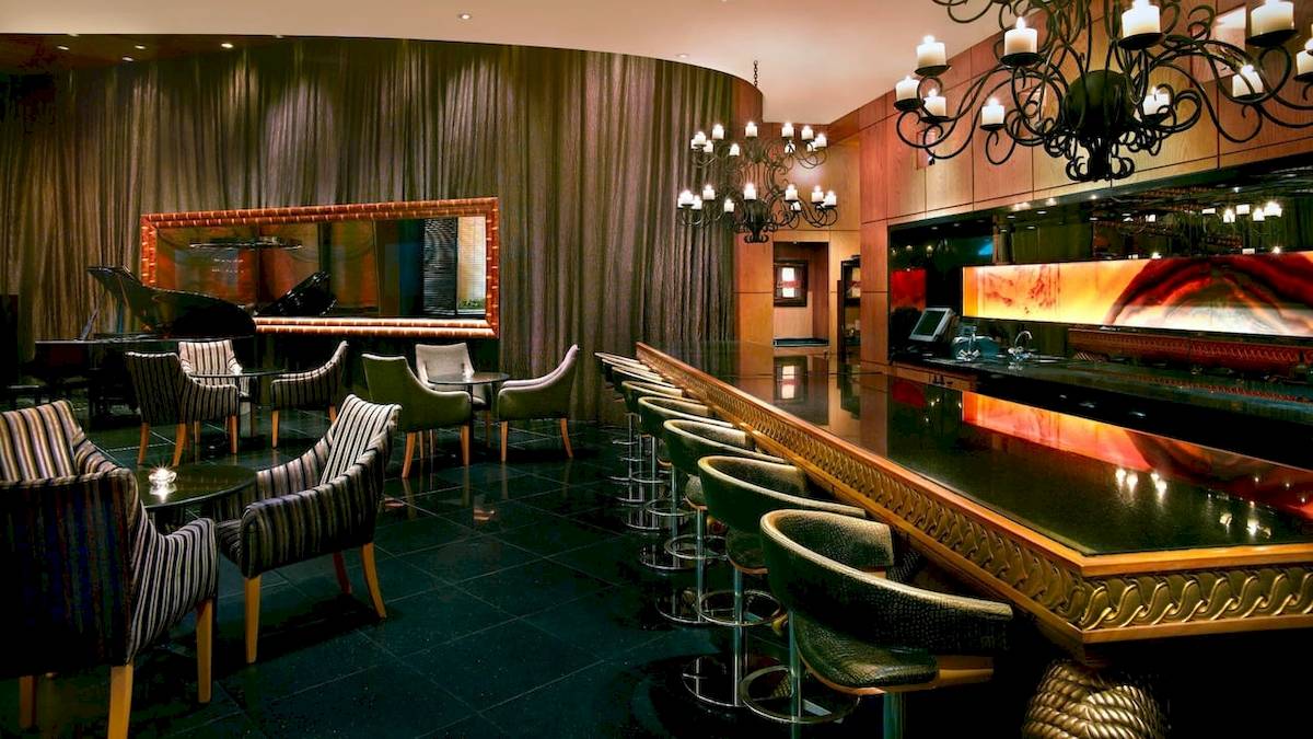 Loungebereich im Grand Hyatt Dubai Hotel mit Klavier, Stühlen und Bar.