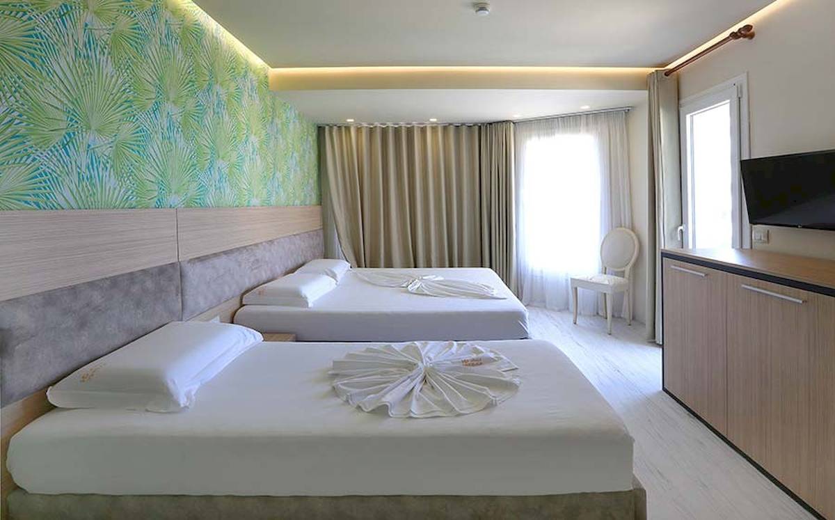 Doppelzimmer im Dyrrah Hotel mit zwei Betten, einem Fernseher und einer Fensterbank.