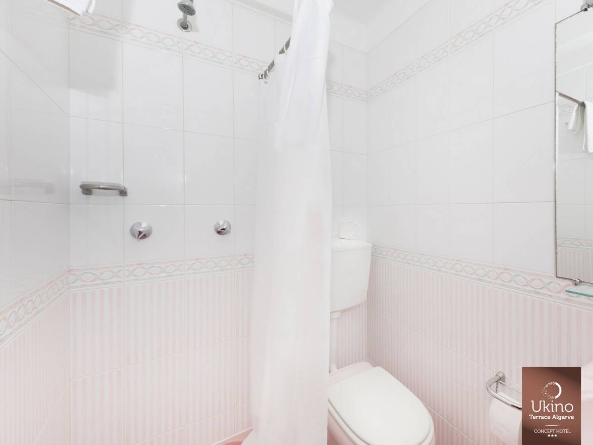 Badezimmer im Ukino Terrace Algarve Hotel mit weißer Dusche und rosa Akzenten.