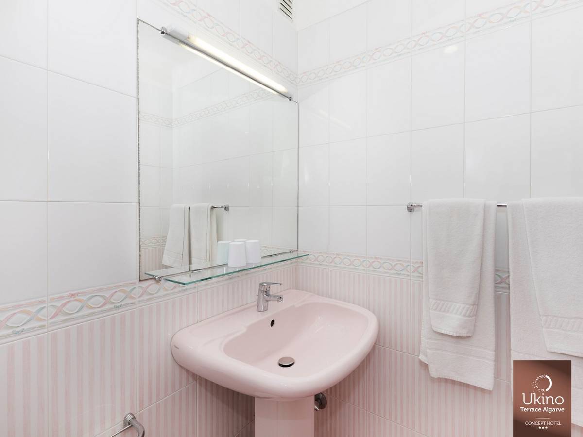 Ein Badezimmer mit einem weißen Waschbecken, einem Spiegel und Handtüchern auf einem Halter.