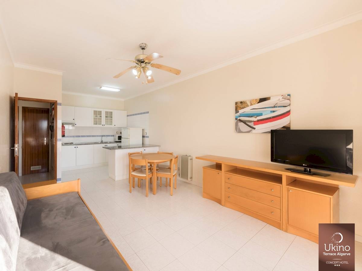 Inneneinrichtung des Ukino Terrace Algarve Hotels mit Wohnzimmer, Tisch, Fernseher und Küche