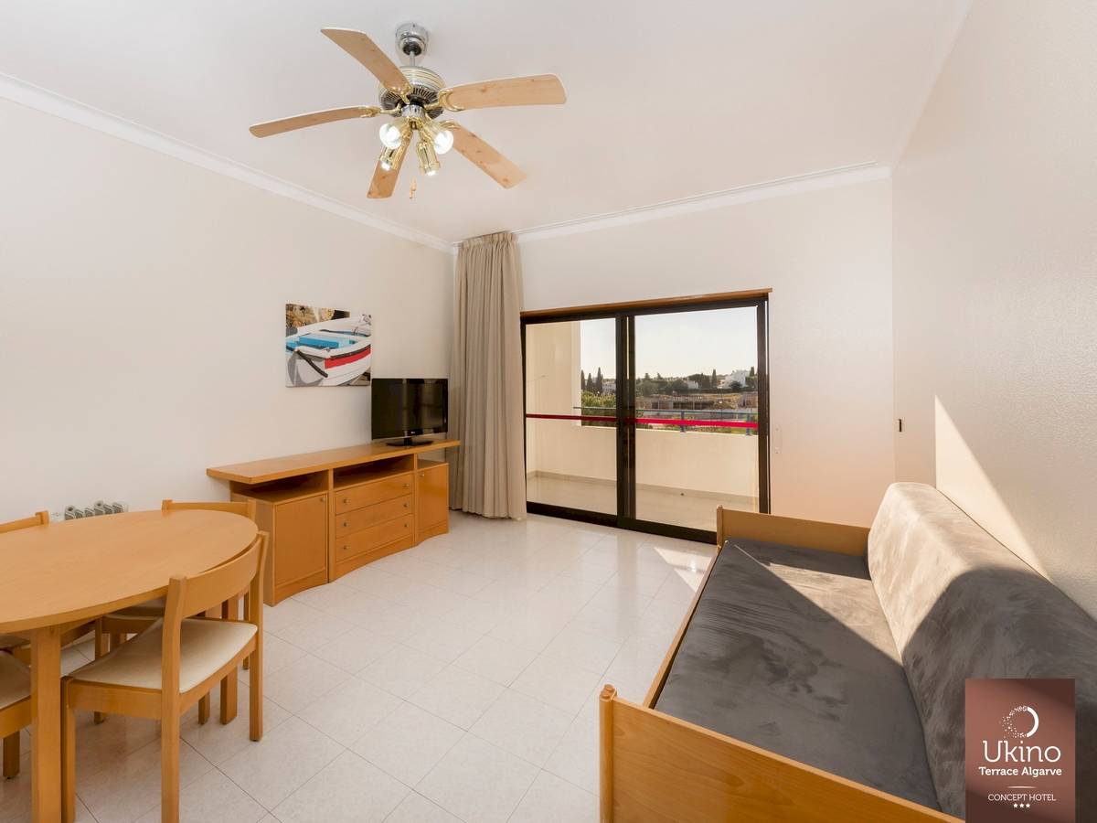 Inneneinrichtung eines Zimmers im Ukino Terrace Algarve Hotel mit Tisch, Stühlen, Fernseher und Balkon