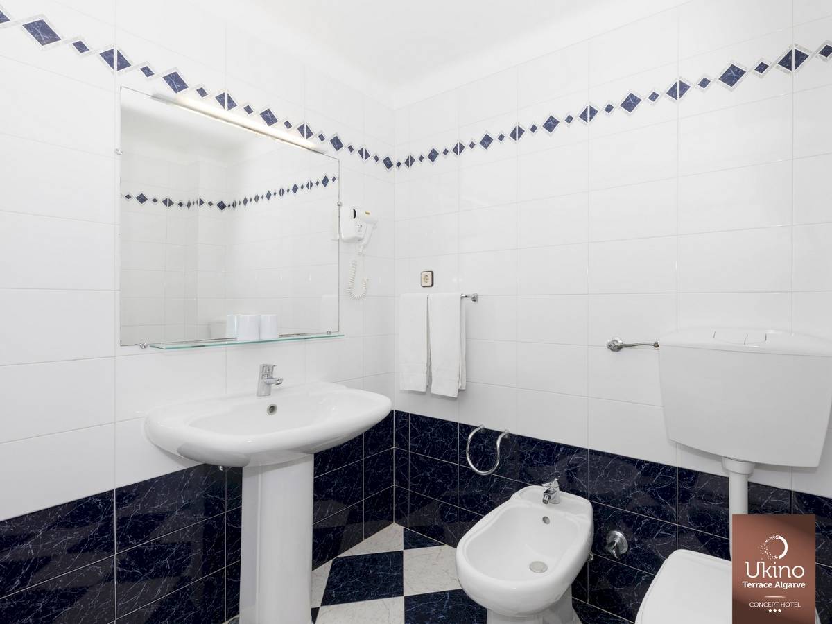 Badezimmer im Ukino Terrace Algarve Hotel mit weißem Waschbecken und Bidet neben einer Toilette.