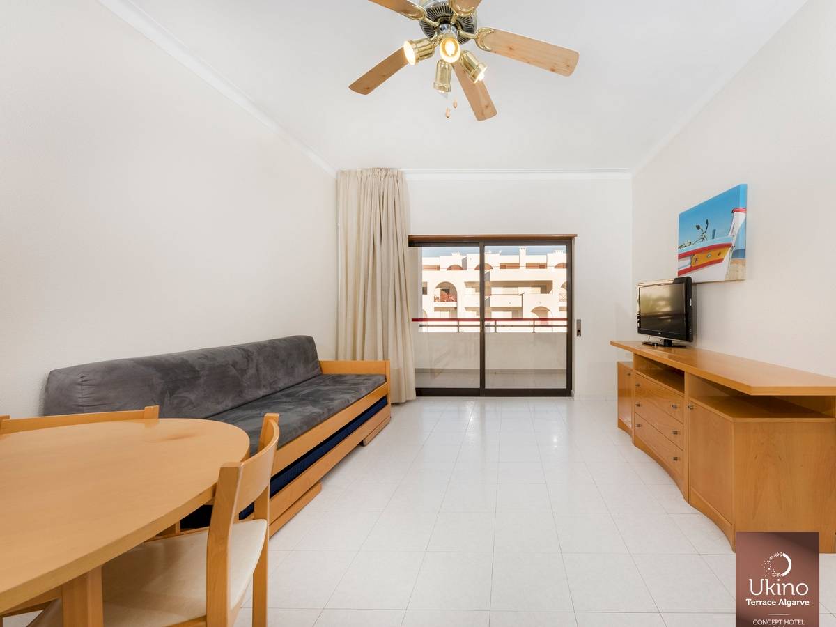Wohnzimmer im Ukino Terrace Algarve Hotel mit Sofa, Tisch, Fernseher und Deckenventilator