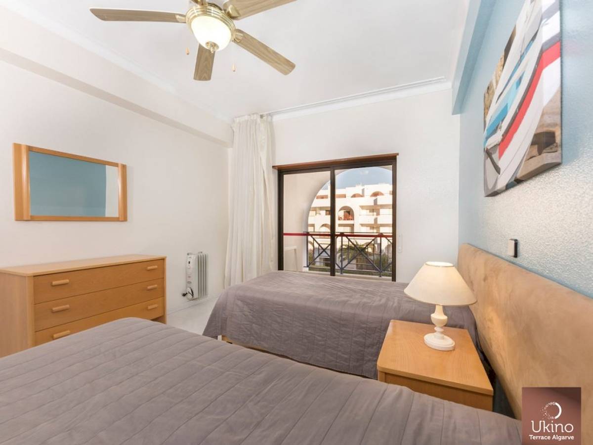 Schlafzimmer im Ukino Terrace Algarve mit zwei Betten, Nachttischen, Lampen und einem Fenster mit Balkon.