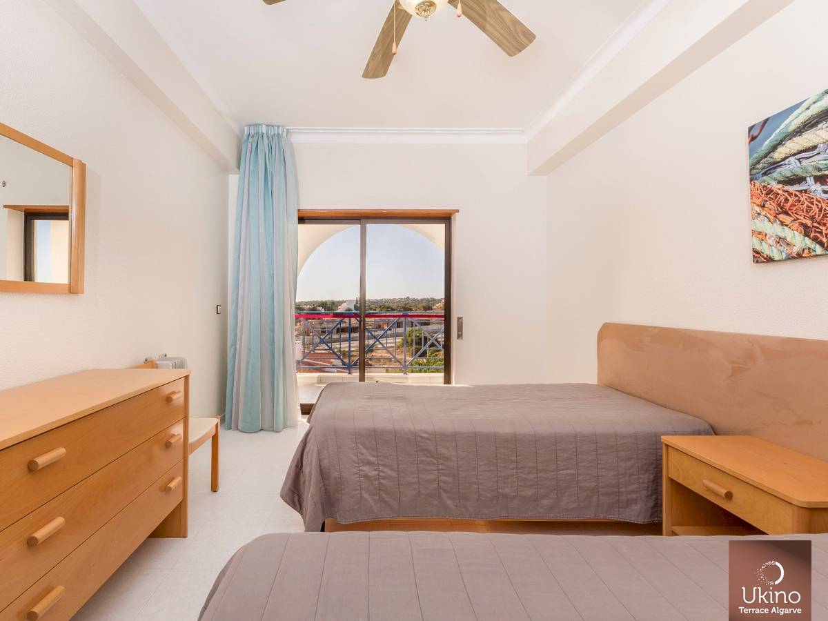 Schlafzimmer im Ukino Terrace Algarve Hotel mit zwei Betten, Kleiderschrank, Nachttisch und Balkonzugang.