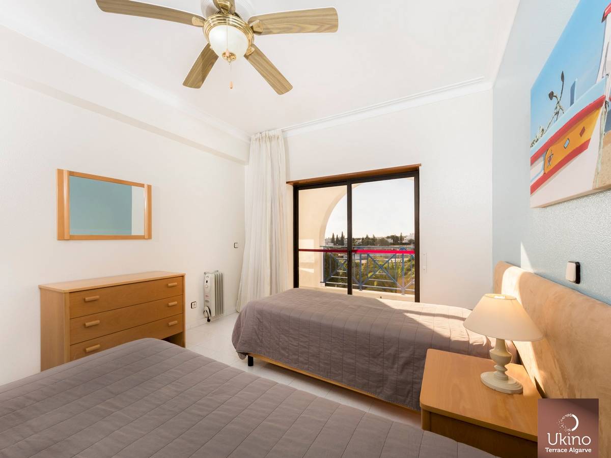 Schlafzimmer im Ukino Terrace Algarve Hotel mit zwei Betten, Nachttischen, Lampe, Spiegel und Klimaanlage.