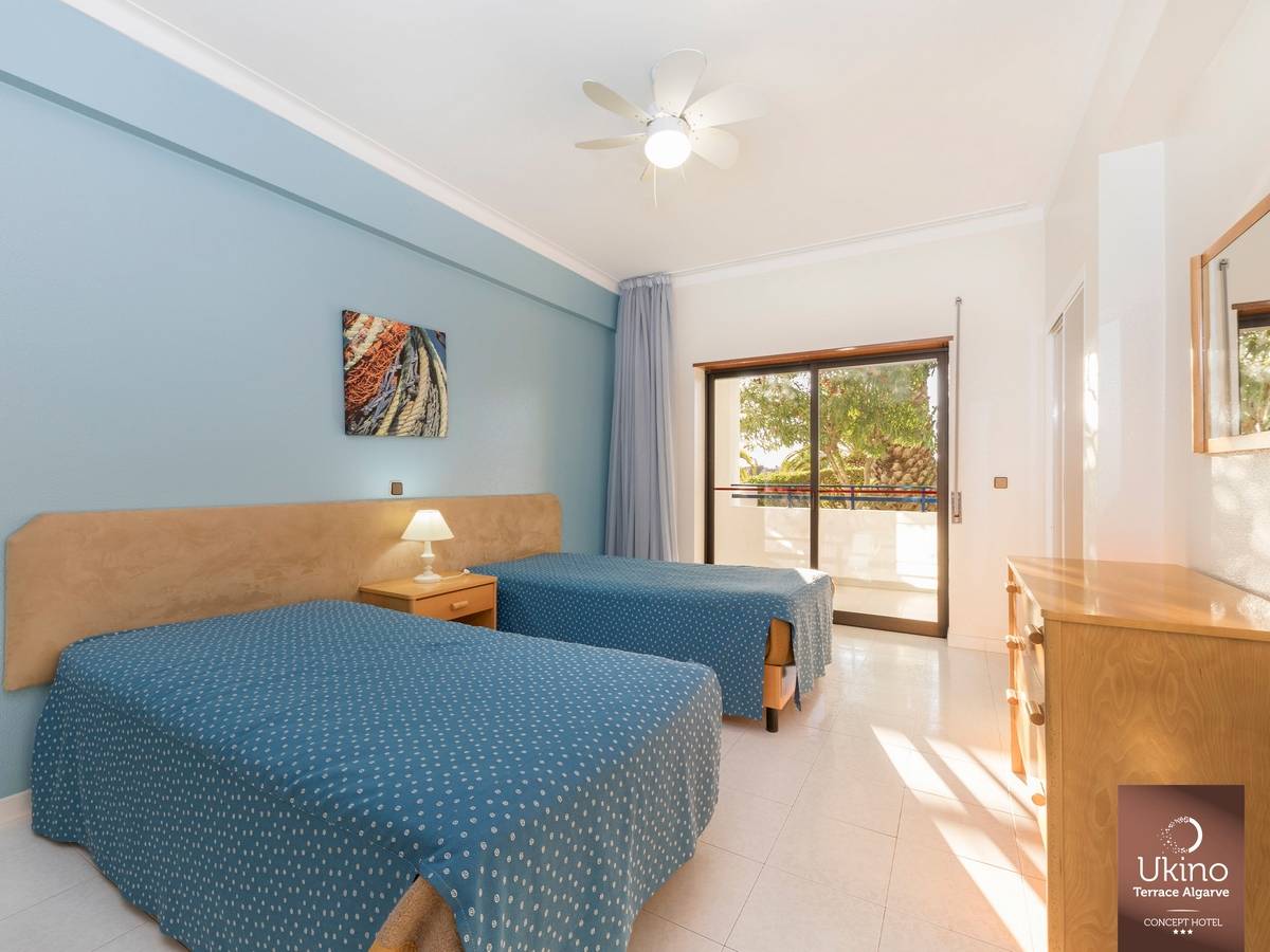 Doppelzimmer im Ukino Terrace Algarve mit zwei Betten, Klimaanlage und Terrassenzugang.
