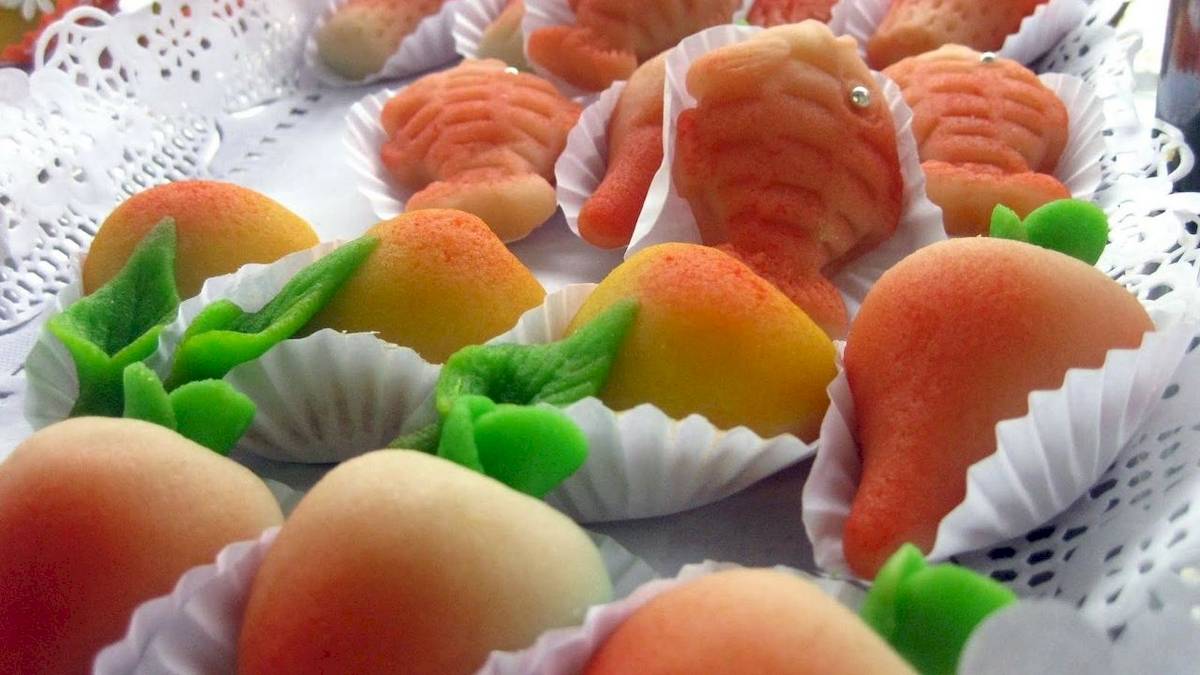 Nahaufnahme von verschiedenen fisch- und aprikosenförmigen kuchen in weißen papierförmchen