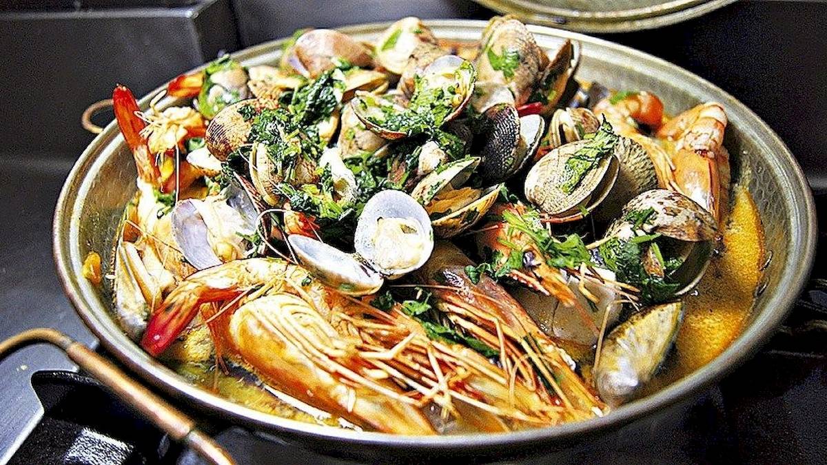 Muschelsuppe in einem Topf auf dem Herd, gefüllt mit Muscheln, Garnelen und Kräutern.