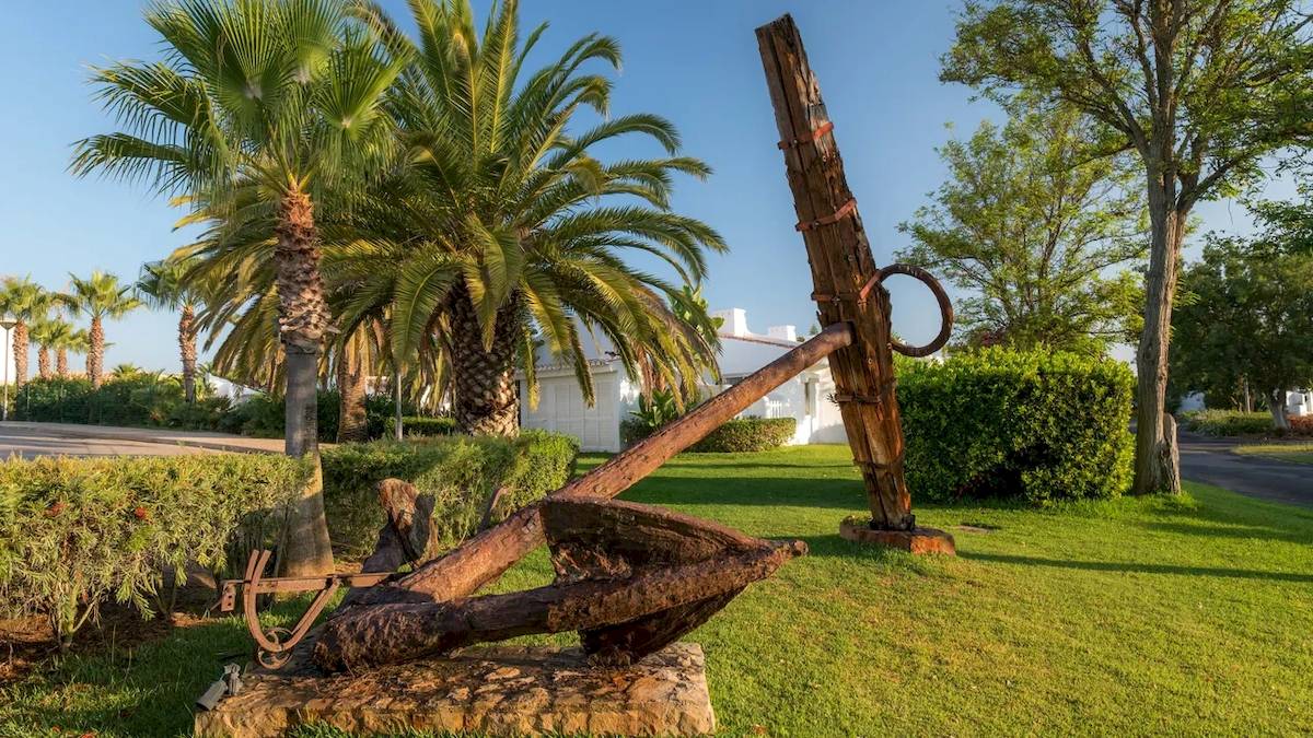 Außenbereich des Ancora Park Hotels mit einer großen Ankerskulptur auf einem Rasen.