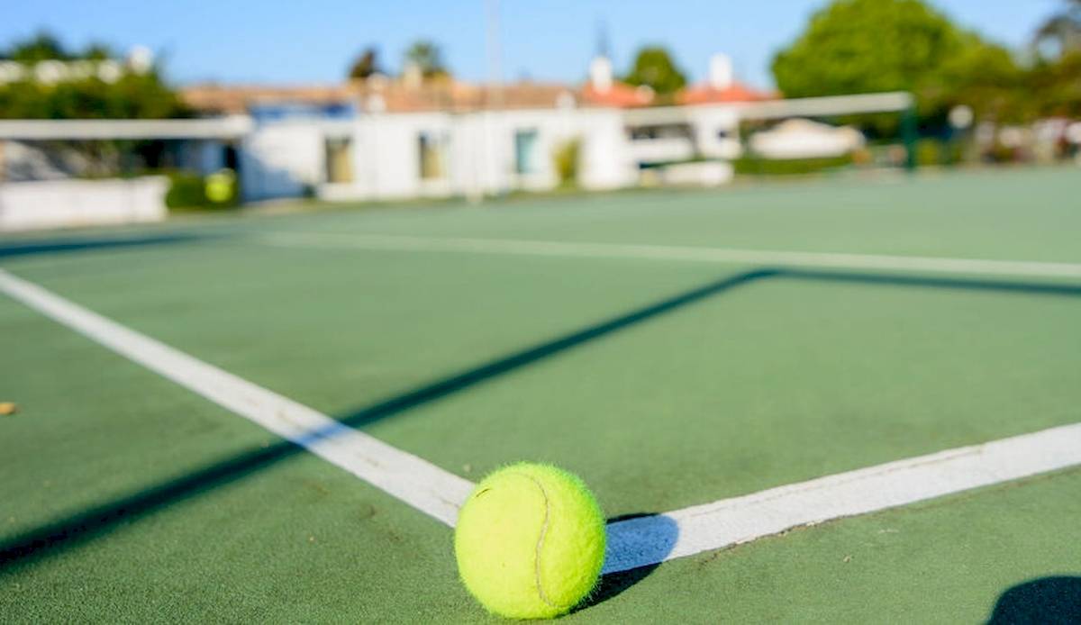 Tennisball auf einem Tennisplatz im Schatten des Netzes