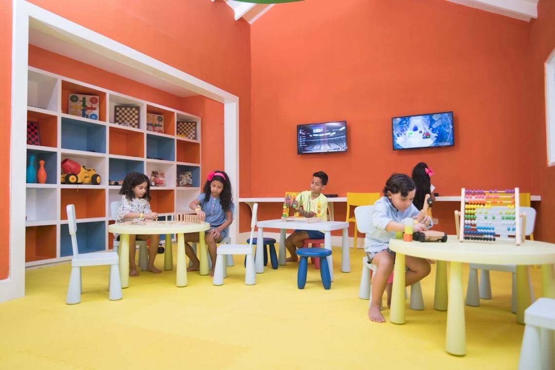 Kinder spielen in einem farbenfrohen Zimmer mit Tischen und Stühlen.