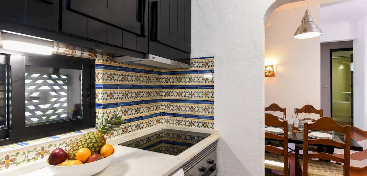 Küche im Pedras da Rainha Resort mit Obstschale, gefliester Wand und Esstisch