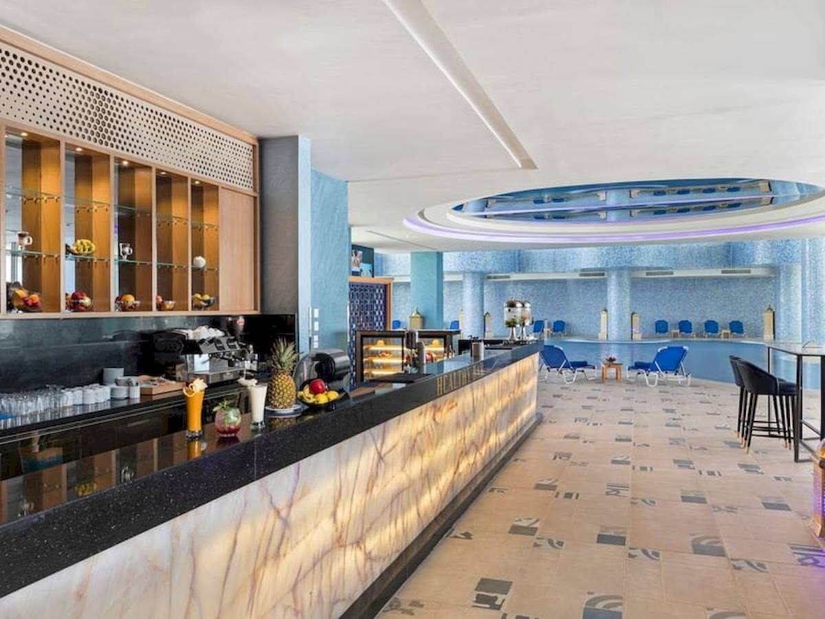 Rezeption im Pickalbatros Blu Spa Resort mit moderner Einrichtung, Marmortheke und blauen Stühlen.