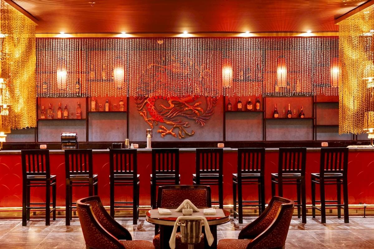 Innenansicht der Bar im Pickalbatros Blu Spa Resort mit roten Stühlen und Tisch.