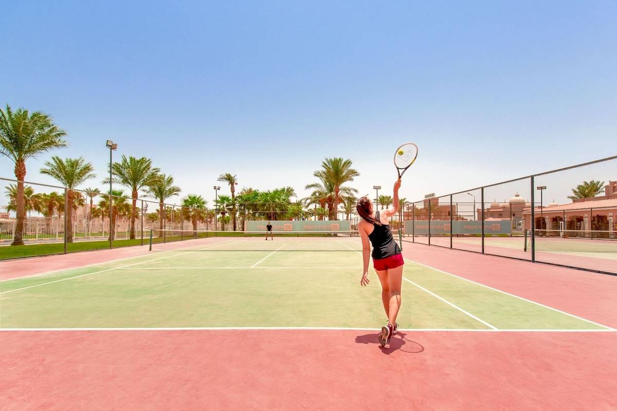 Tennisplatz im Pickalbatros Aqua Vista Resort mit einer Spielerin, die einen Ball schlägt.