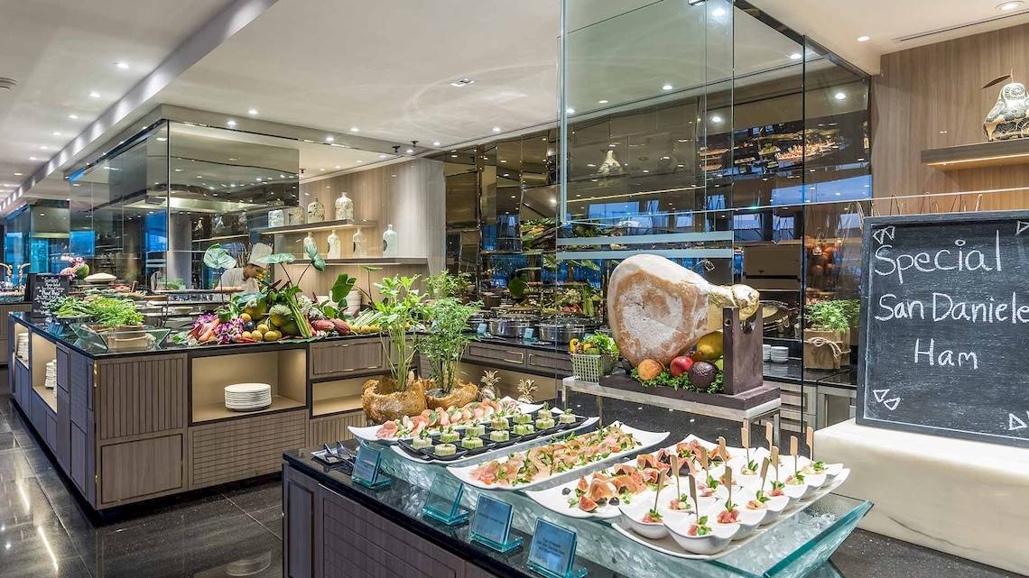Buffet im Chatrium Hotel Riverside Bangkok mit verschiedenen Gerichten und einem großen schwarzen Brett.