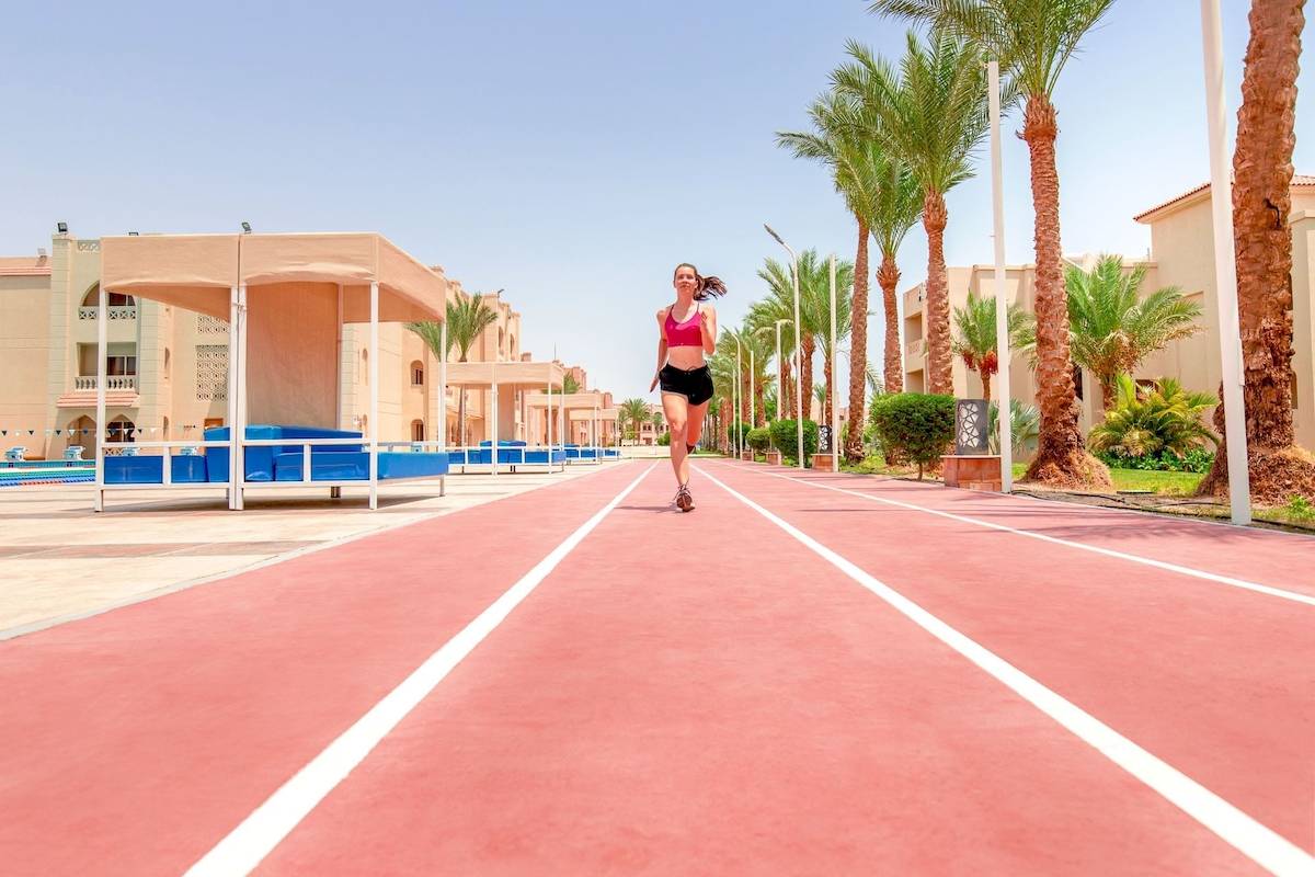 Eine Frau joggt auf einer roten Laufbahn vor dem Pickalbatros Aqua Vista Resort.