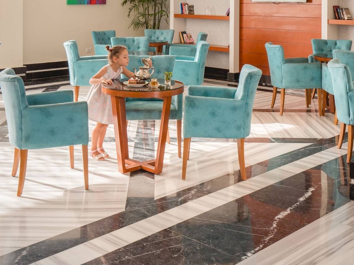 Ein Mädchen sitzt in einem blauen Stuhl in der Lobby des Pickalbatros Aqua Vista Resort Hotels.