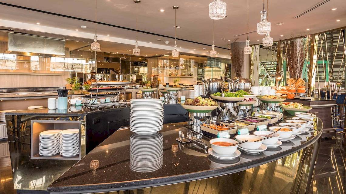 Buffetbereich im Chatrium Hotel Riverside Bangkok mit verschiedenen Speisen und Geschirr.