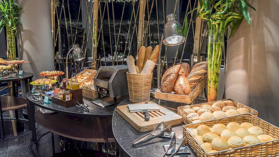 Frühstücksbuffet im Chatrium Hotel Riverside Bangkok mit verschiedenen Brotsorten, Gebäck und Dekoration.