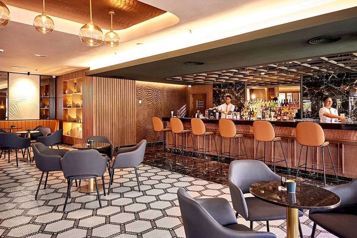 Innenansicht der Bar im RIU Palace Macao Hotel mit Barkeepern und gepolsterten Stühlen.