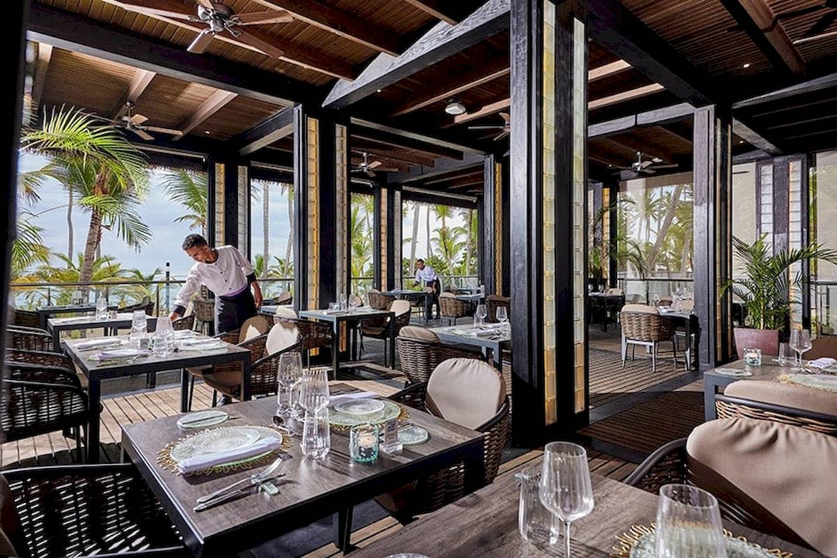 Das RIU Palace Macao Innenrestaurant mit Tischen, Stühlen und einem Kellner, der die Tische einrichtet.