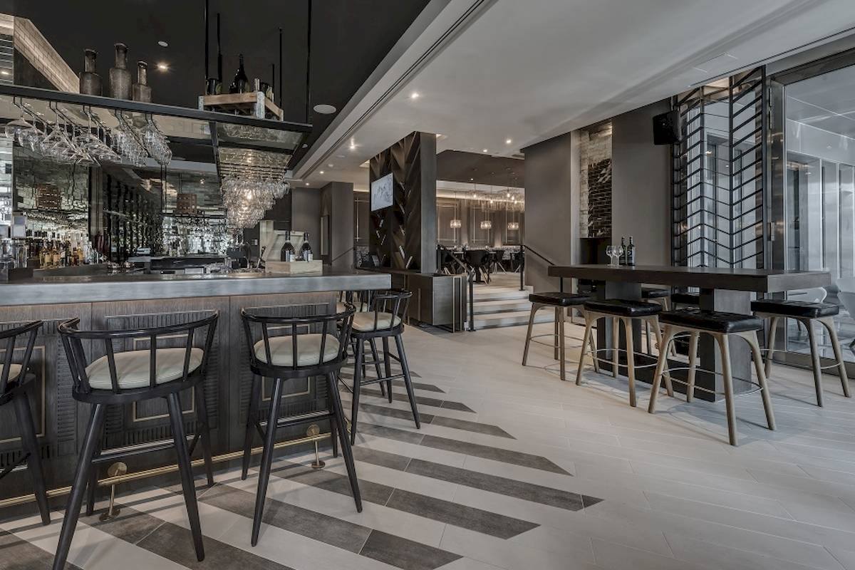 Innenansicht der Bar im Al Bandar Rotana Hotel mit Barhockern und moderner Einrichtung.