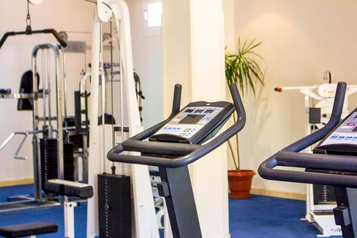Fitnessstudio im Golden Beach Resort mit Laufband und Hanteln neben einer Zimmerpflanze