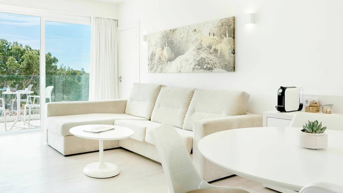 Wohnzimmer im Iberostar Cristina Hotel mit Sofa, Tisch und Aussicht auf den Garten.