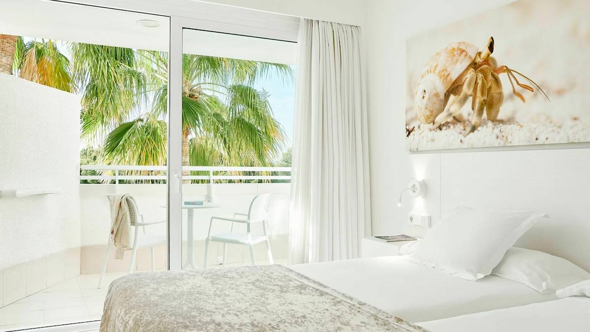 Zimmer im Iberostar Cristina Hotel mit Terrasse und Ausblick auf Palmen und Meer.