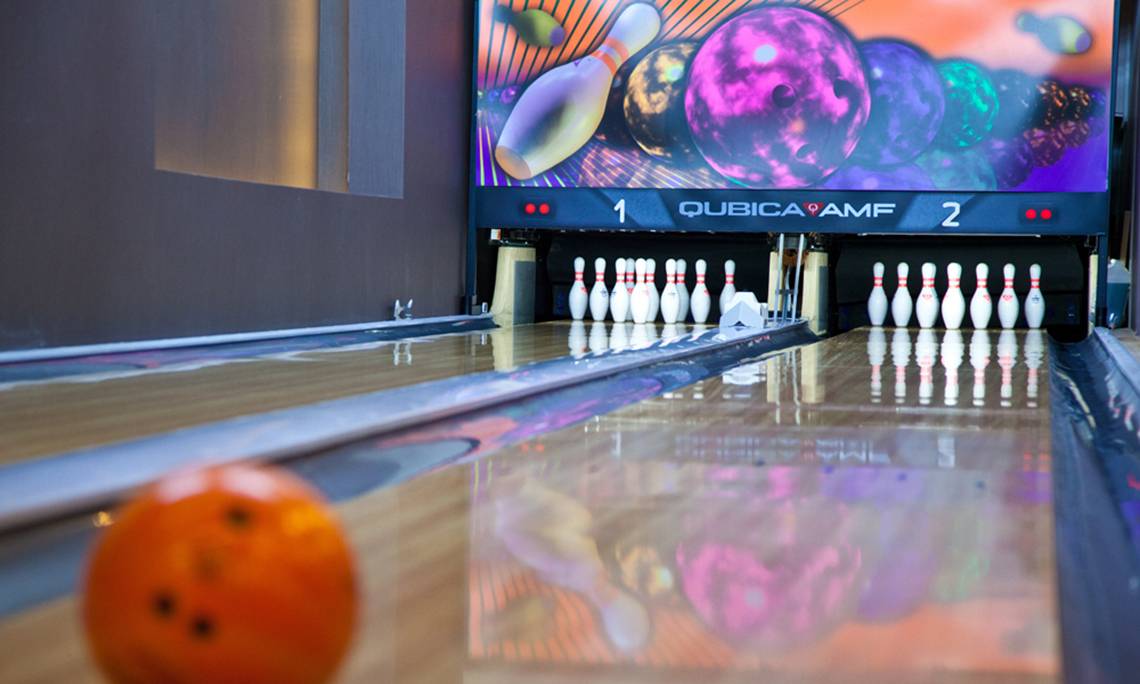 Bowlingbahn im Sherwood Dreams Resort mit Pins und Ball, Fernseher zeigt Spiel.