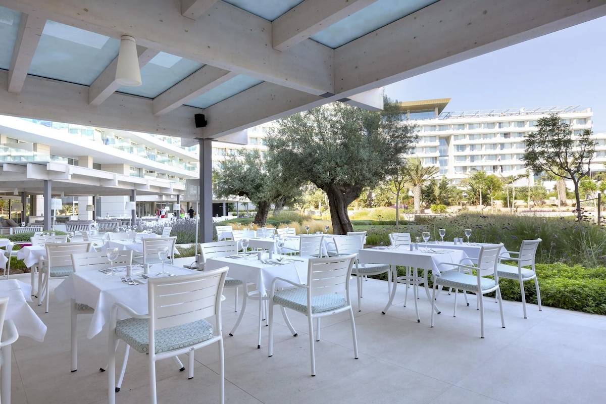 Restaurantterrasse im Hipotels Gran Playa de Palma mit weißen Tischen und Stühlen.