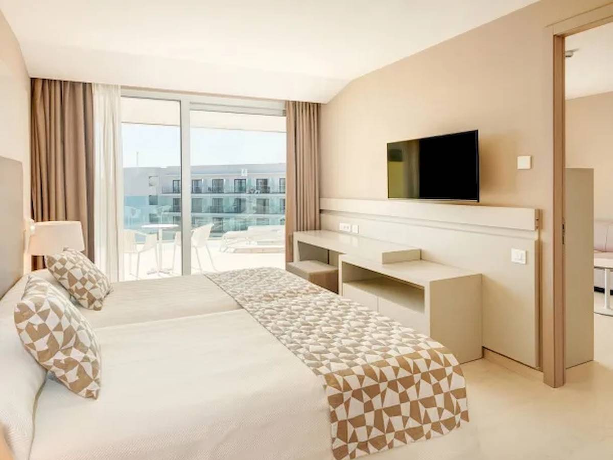 Ein Hotelzimmer mit Doppelbett, Fernseher, Schreibtisch und Meerblick.