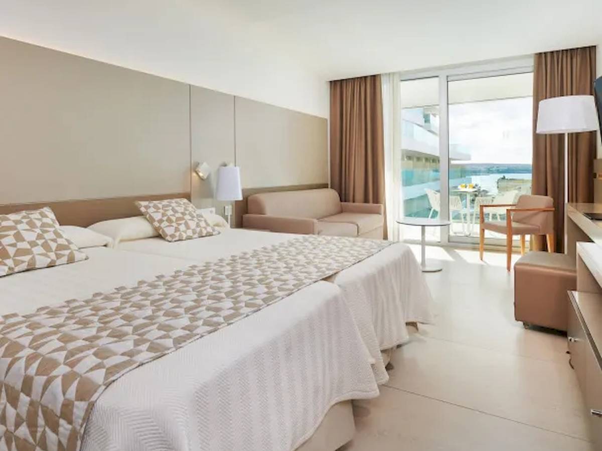 Schlafzimmer im Hipotels Gran Playa de Palma mit zwei Betten, einem Sofa und einem Tisch mit Blick auf das Meer.